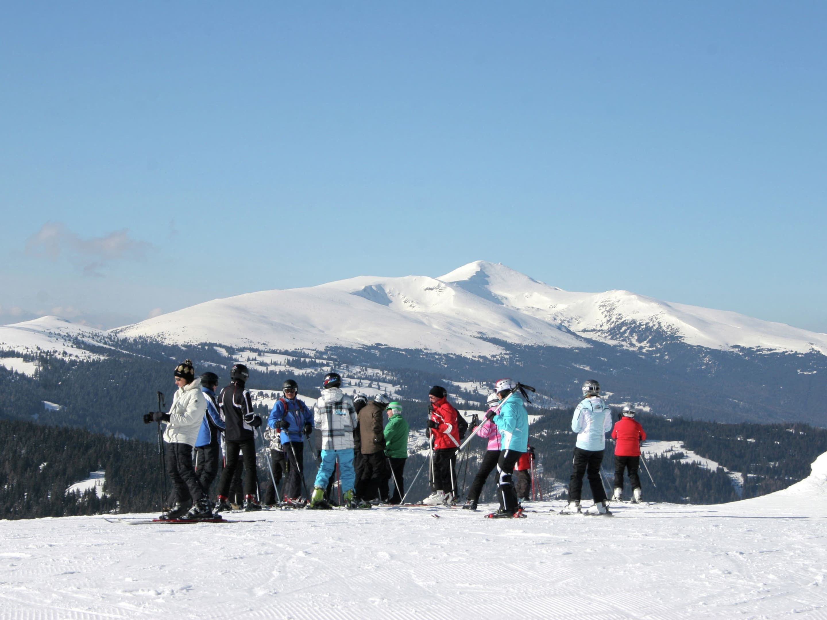 A group of skiers on a snowy mountain with a clear sky.