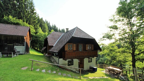 A traditional chalet with a sloped roof, wooden balcony, and a stone pathway leading to the entrance.