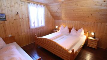 Una habitación con paneles de madera, una cama doble, dos mesitas de noche con lámparas, una ventana con cortinas y un cuadro enmarcado en la pared.