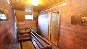 A wooden interior with a bench, a radiator, and a door.