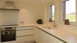A modern kitchen with a built-in oven, a coffee maker, and a window with a view of the outdoors. - Countryside Holiday Home in Theux With Fenced Garden and BBQ (Theux)