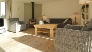 A cozy living room with a fireplace, wicker furniture, and a television. - Countryside Holiday Home in Theux With Fenced Garden and BBQ (Theux)