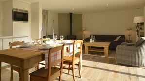 A dining area with a wooden table and chairs, a sofa, and a fireplace. - Countryside Holiday Home in Theux With Fenced Garden and BBQ (Theux)
