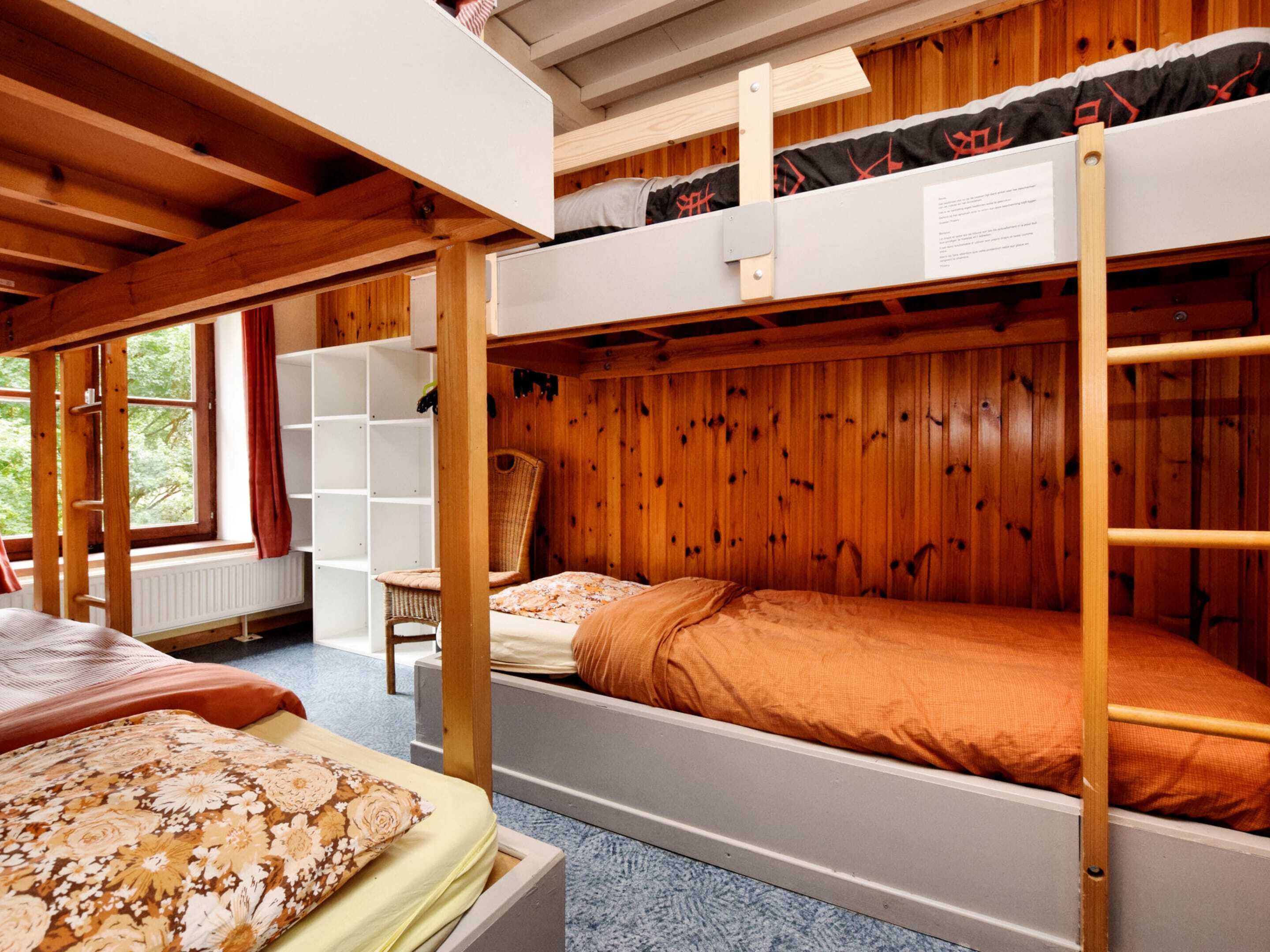 Une chambre avec un lit superposé, des murs en bois, une fenêtre et une chaise.