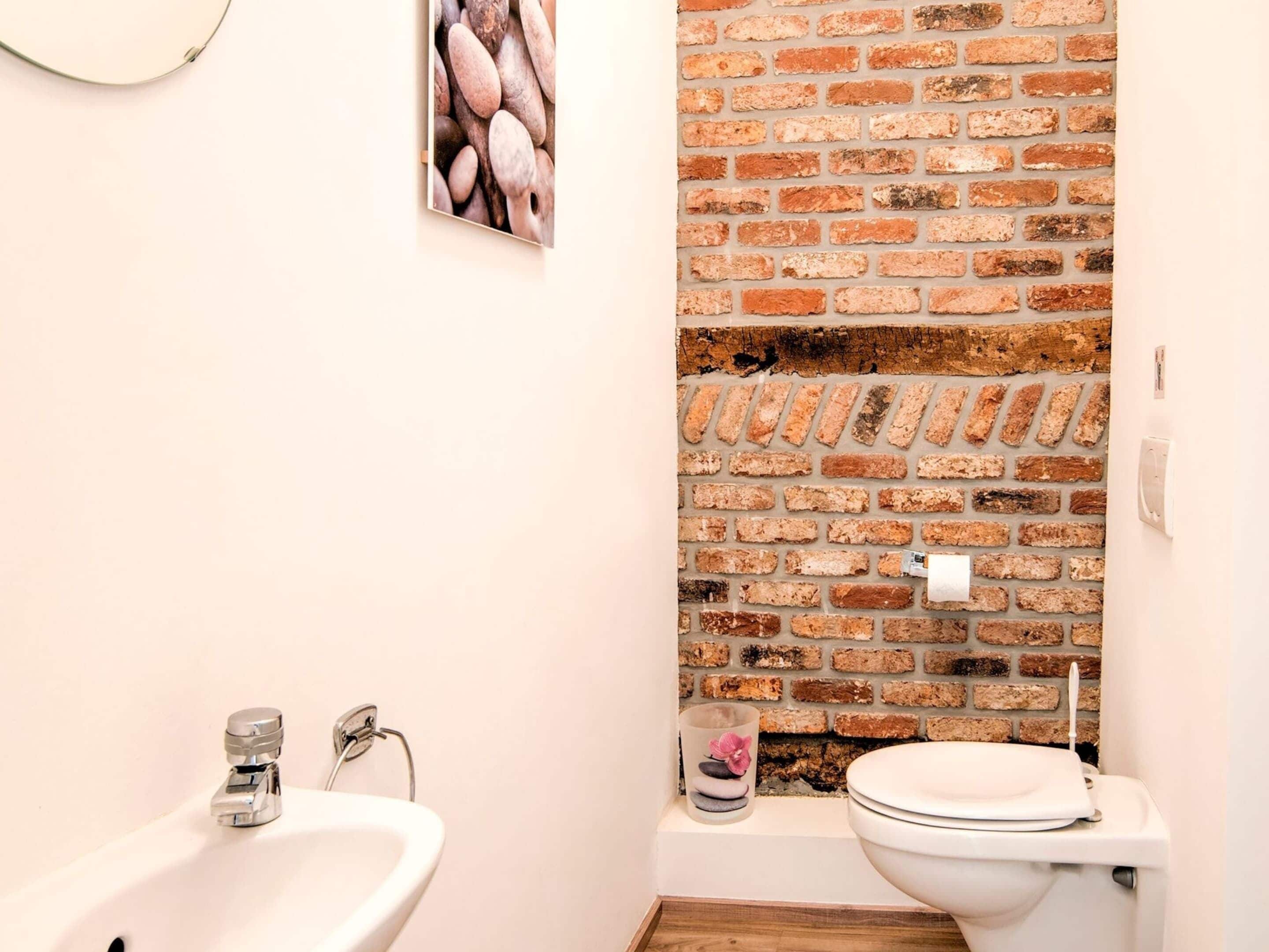 Un baño con pared de ladrillo, un lavabo y un inodoro.