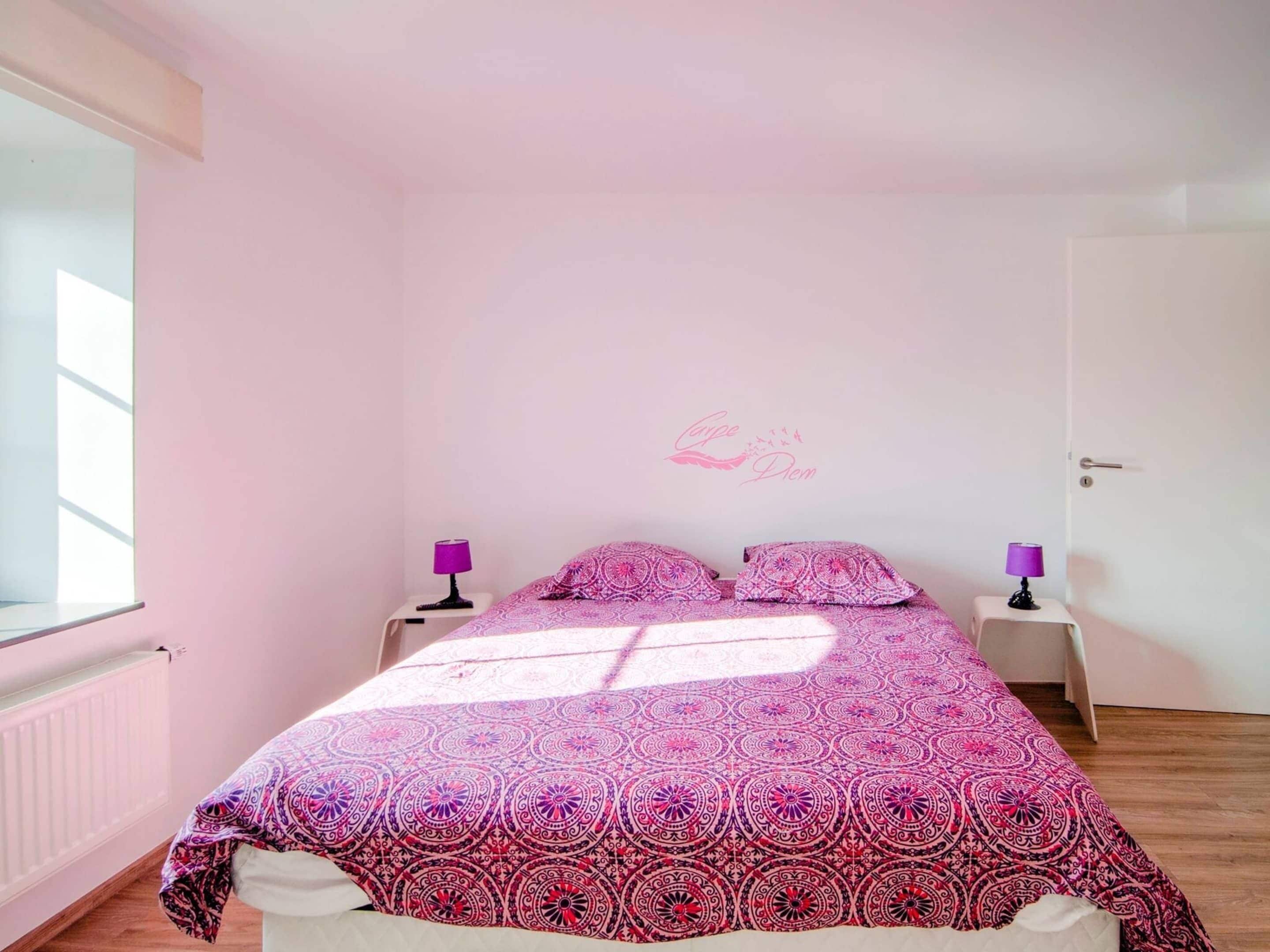 A bedroom with a bed, two nightstands, a door, and a window.