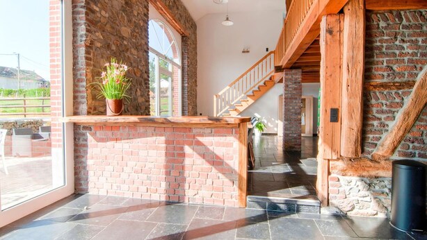 A spacious interior with a stone wall, a wooden staircase, and a large window. - Liege Villa Near Spa Circuit (Malmedy)