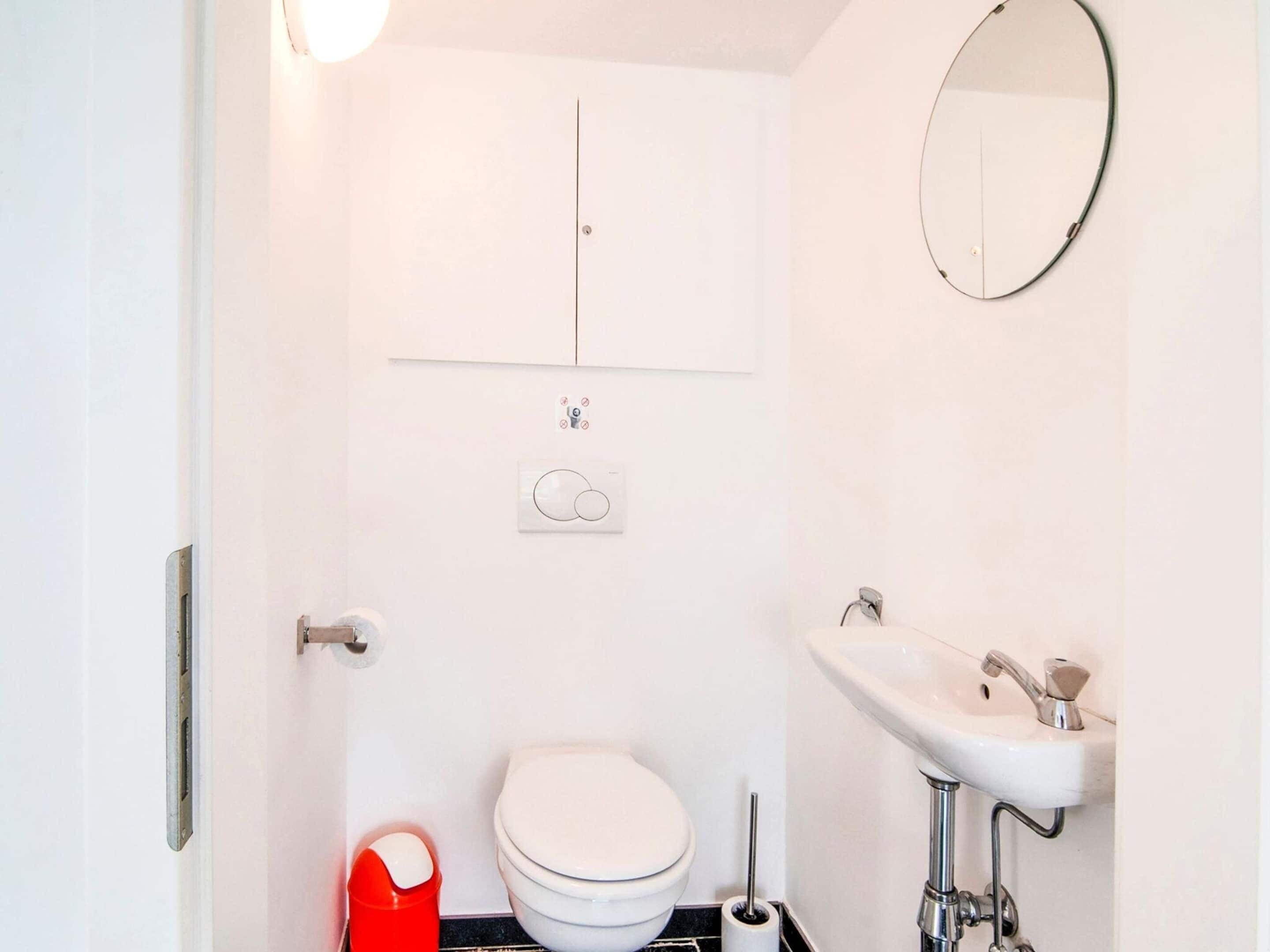 Un bagno piccolo e bianco con il water, un lavandino e uno specchio.