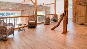 A spacious balcony with wicker furniture, a stone wall, and a wooden ceiling structure. - Liege Villa Near Spa Circuit (Malmedy)