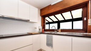 Eine Küche mit weißen Schränken, einem Holzfensterrahmen, einem eingebauten Herd und einer gefliesten Rückwand.