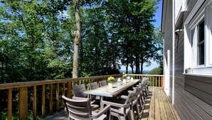 A wooden deck with a table and chairs, surrounded by trees and overlooking a body of water. - Spacious Family Villa in Soy (Erezee)