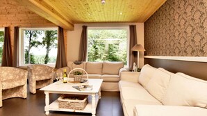 A cozy living room with a wooden ceiling, a beige sofa, a white coffee table, and a patterned wall. - Spacious Family Villa in Soy (Erezee)
