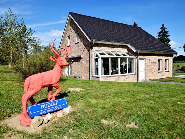 A building with a brick facade, a glass entrance, and a deer sculpture in front.