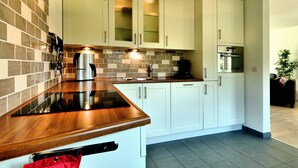 A modern kitchen with white cabinets, a wooden countertop, and a tiled backsplash. - Wheelchair-friendly House With Sauna (Buetgenbach)