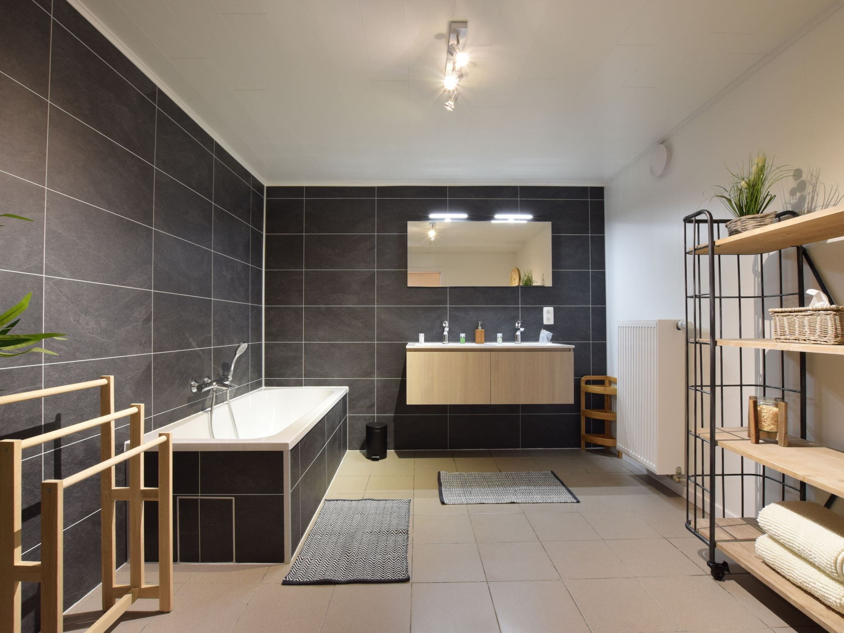 A modern bathroom with a freestanding bathtub, a vanity with a mirror, and a radiator.