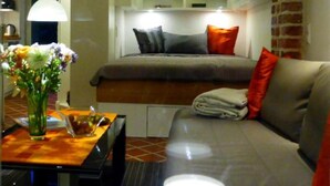 A compact room with a bed, a sofa, a table with a vase of flowers, and a hanging light fixture. - Apartments gatehouse - old town (Lüneburg)