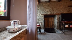 Une cuisine avec un mur en pierre, une cheminée et un téléviseur.