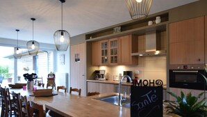 A modern kitchen with wooden cabinets, a central island with bar stools, pendant lighting, and a Bosch oven. - Wonderful Country House With Huge Garden (Poperinge)