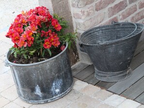 Twee grote metalen bloempotten op een betegeld terras.