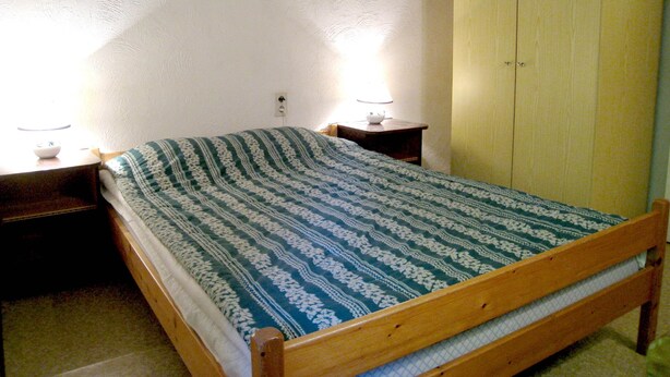 A single bed with a patterned bedspread, a bedside table with a lamp, and a wooden wardrobe. - Farmhouse in Basse-bodeux Near Forest (Trois-Ponts)