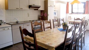 A kitchen with white cabinets, a sink, a stove, and a dining table with chairs. - Farmhouse in Basse-bodeux Near Forest (Trois-Ponts)