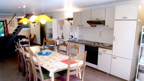 A kitchen with a dining table, chairs, and a staircase leading to another level. - Farmhouse in Basse-bodeux Near Forest (Trois-Ponts)
