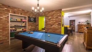 A pool table in a room with brick walls, a bookshelf, and a dartboard. - Cozy Holiday Home in Theux (Theux)