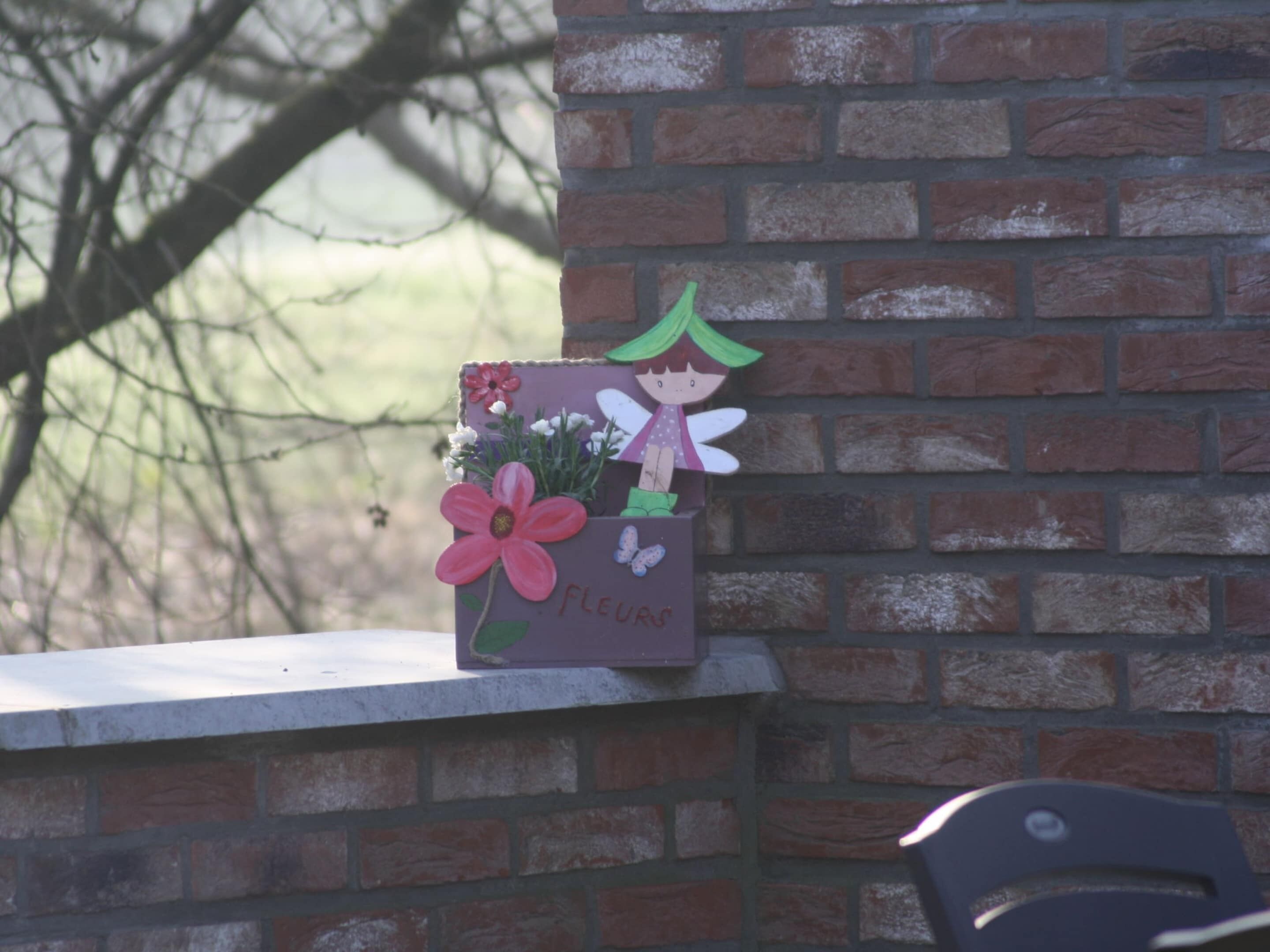 Un muro di mattoni con un rilievo decorativo raffigurante una fata che tiene un fiore.