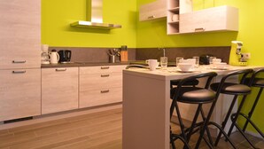 A modern kitchen with light wood cabinets, a stainless steel range hood, and a bar area with stools. - Cozy Holiday Home in Theux (Theux)