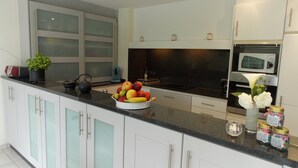 Een moderne keuken met witte kasten, een zwart aanrecht en een fruitschaal.