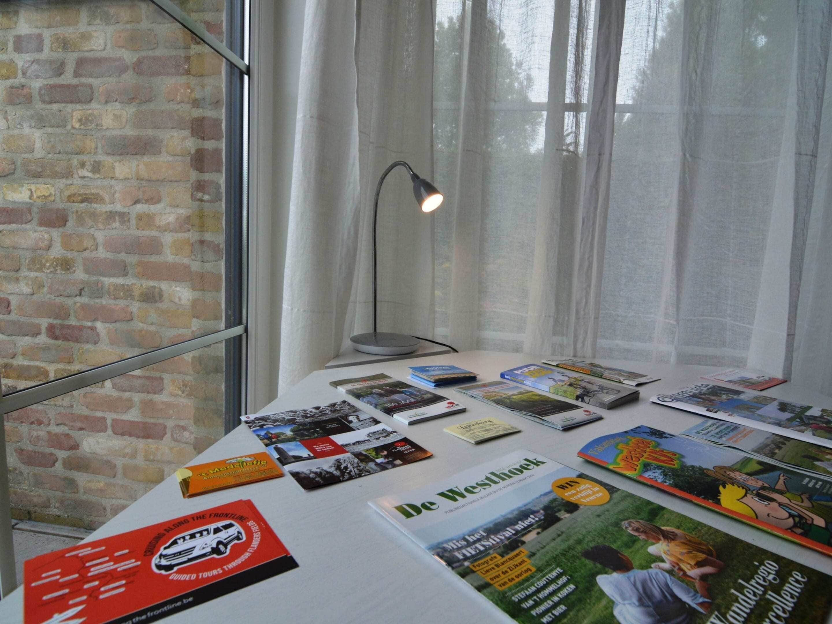 Une table sur laquelle sont disposées diverses brochures de voyage et une lampe.
