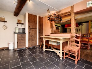 Une cuisine avec une table en bois, une chaise, un four à micro-ondes et un placard.