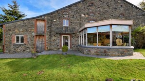 A stone building with a large glass window and a wooden door. - Holiday Home in Vielsalm (Vielsalm)