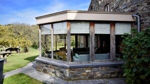 A covered outdoor seating area with stone walls and a view of a grassy yard. - Holiday Home in Vielsalm (Vielsalm)
