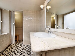 Une salle de bain avec un lavabo blanc, un miroir et un espace douche.