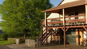 A wooden building with a balcony and a staircase leading to a covered area.