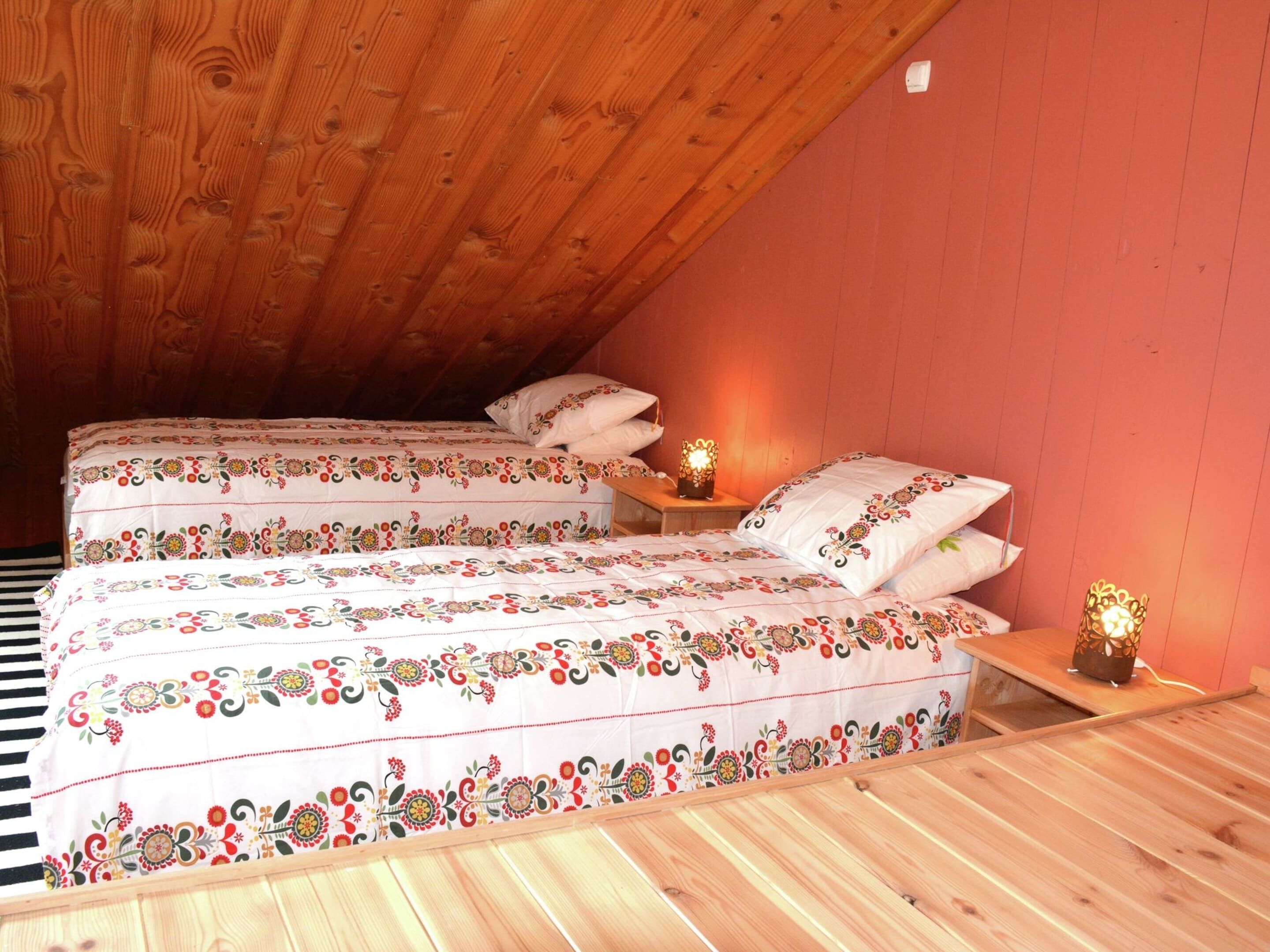 Quarto de sótão aconchegante com duas camas, vigas de madeira e teto inclinado.