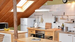 A compact kitchen with a wooden table, a refrigerator, a microwave, and a stove.