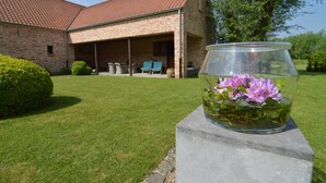 Een gebouw van baksteen met een overdekte patio en een betonnen plantenbak met bloemen.