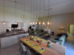 A modern kitchen with a dining area set for a meal, featuring a wooden table, chairs, and a central island with a sink. - Tasteful Holiday Home in Sijsele-brugge With Garden (Damme)
