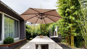 Um deck de madeira com uma mesa e um guarda-sol.