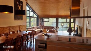 Een moderne keuken met een eethoek, grote ramen en uitzicht op de omgeving.