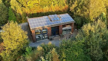 Una casa moderna con techo de paneles solares rodeada de un bosque denso.