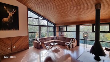 Un salón amplio con un sofá modular grande, una mesa de centro redonda y una chimenea.