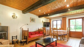 A cozy living room with a wooden ceiling, a sofa, a TV, a dining table with chairs, and a fireplace. - Rustic Vacation Home, Baneux (Lierneux)