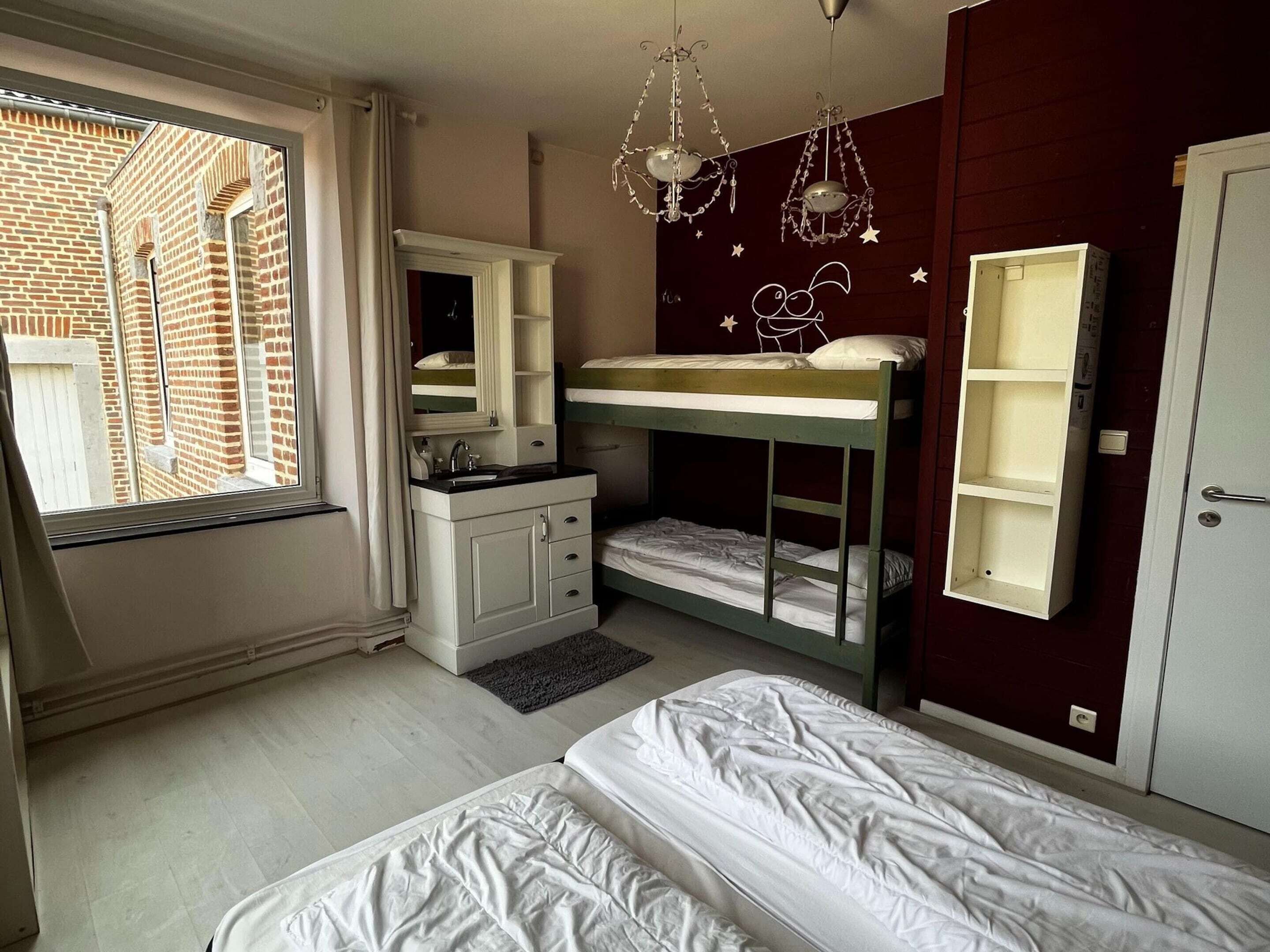 A bedroom with bunk beds, a vanity with a mirror, a window with curtains, and a door.