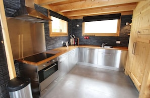 A modern kitchen with a stainless steel range, wooden countertops, and a stone backsplash. - Chalet in La Tzoumaz Near Ski Slopes (Riddes)