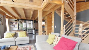 A spacious living area with two sofas, a patterned rug, and a wooden staircase. - Chalet in La Tzoumaz Near Ski Slopes (Riddes)