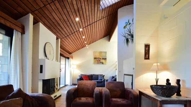 A spacious living room with a high wooden ceiling, a fireplace, and a large window. - Cozy Villa in Vielsalm With Private Garden (Vielsalm)
