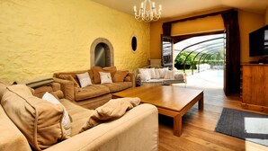 A living room with a large wooden coffee table, two sofas, and a television on a wooden cabinet. - Magnificent Holiday Home in Baronville With Heated Pool & Billiards (Beauraing)